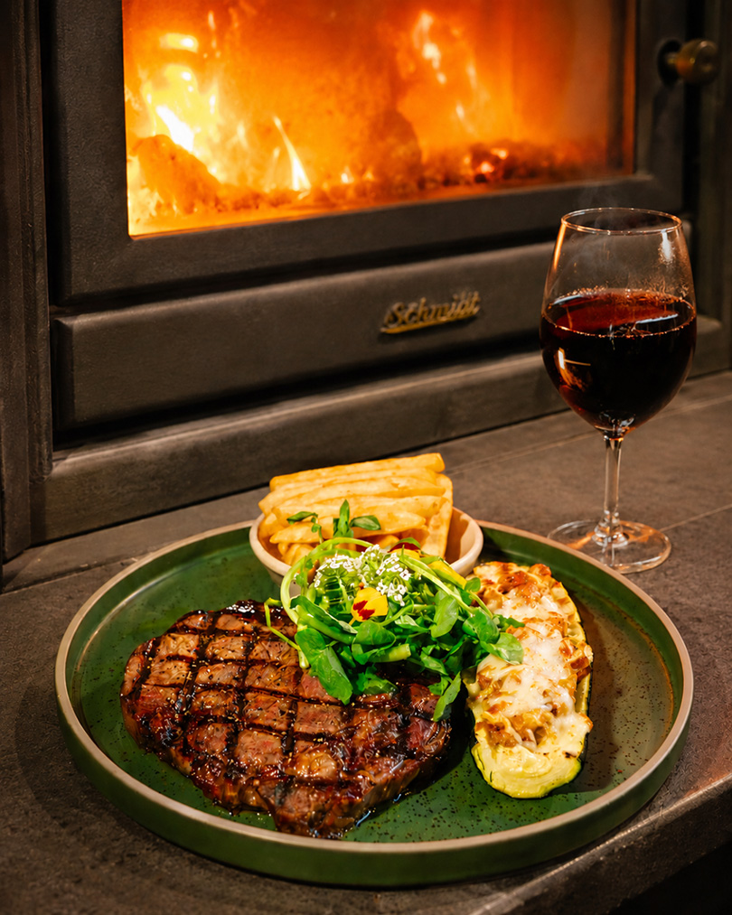 Steak and wine beside the fireplace at Goat House